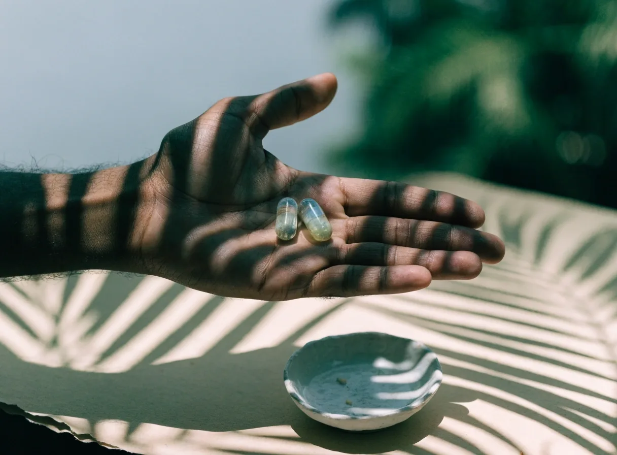 A single translucent capsule on pale paper with a leaf shadow across it